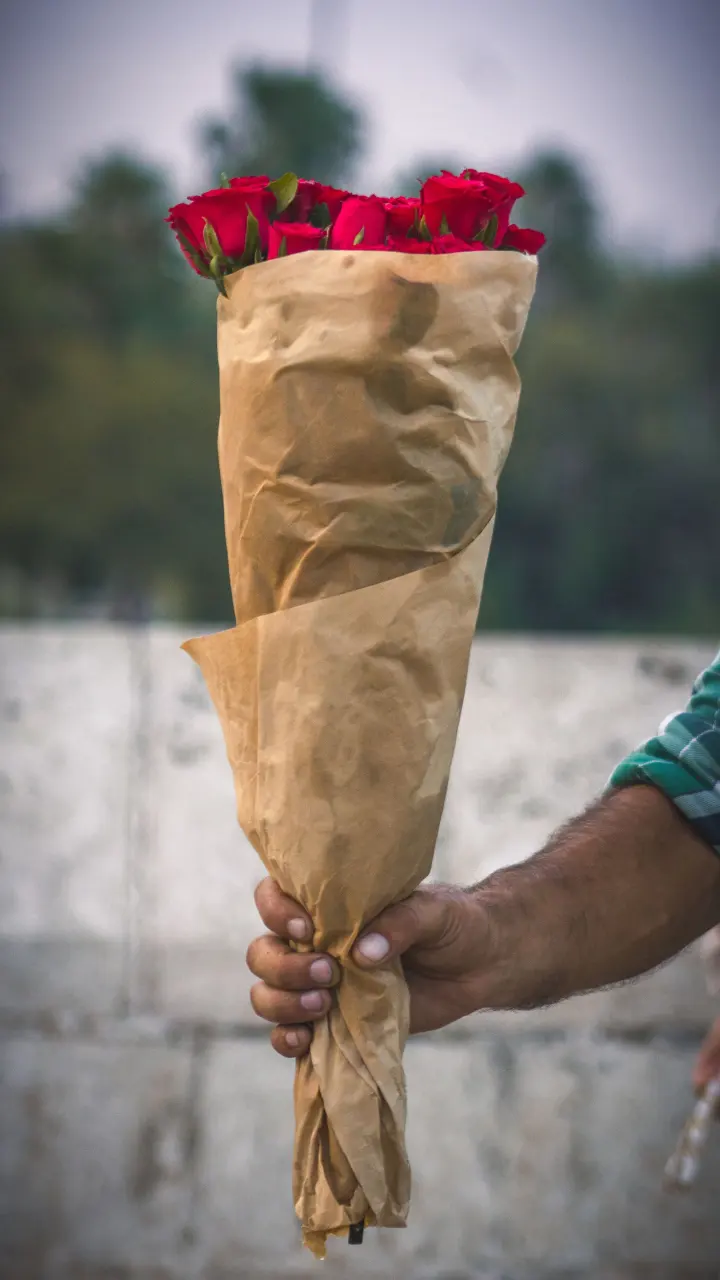 Hombre llevando un ramo de rosas envuelto en kraft