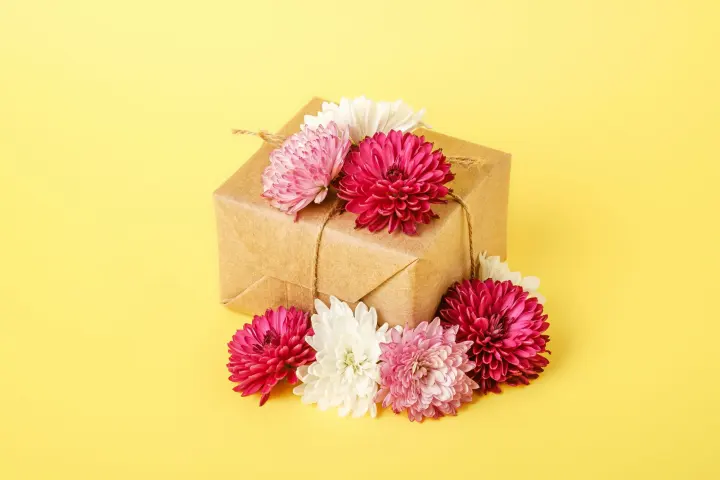 Caja de regalo kraft decorada con flores sobre fondo amarillo