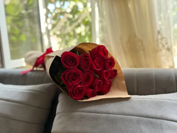 Ramo de rosas rojas en papel kraft sobre un sofá