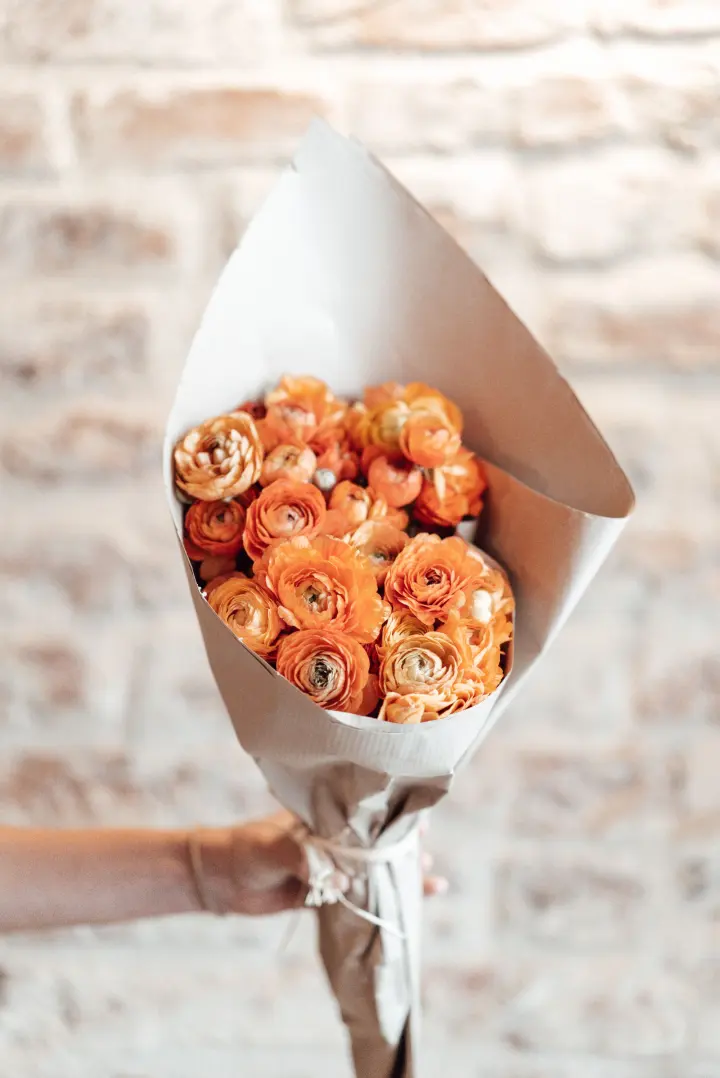 Bouquet de ranúnculos naranjas en papel crema