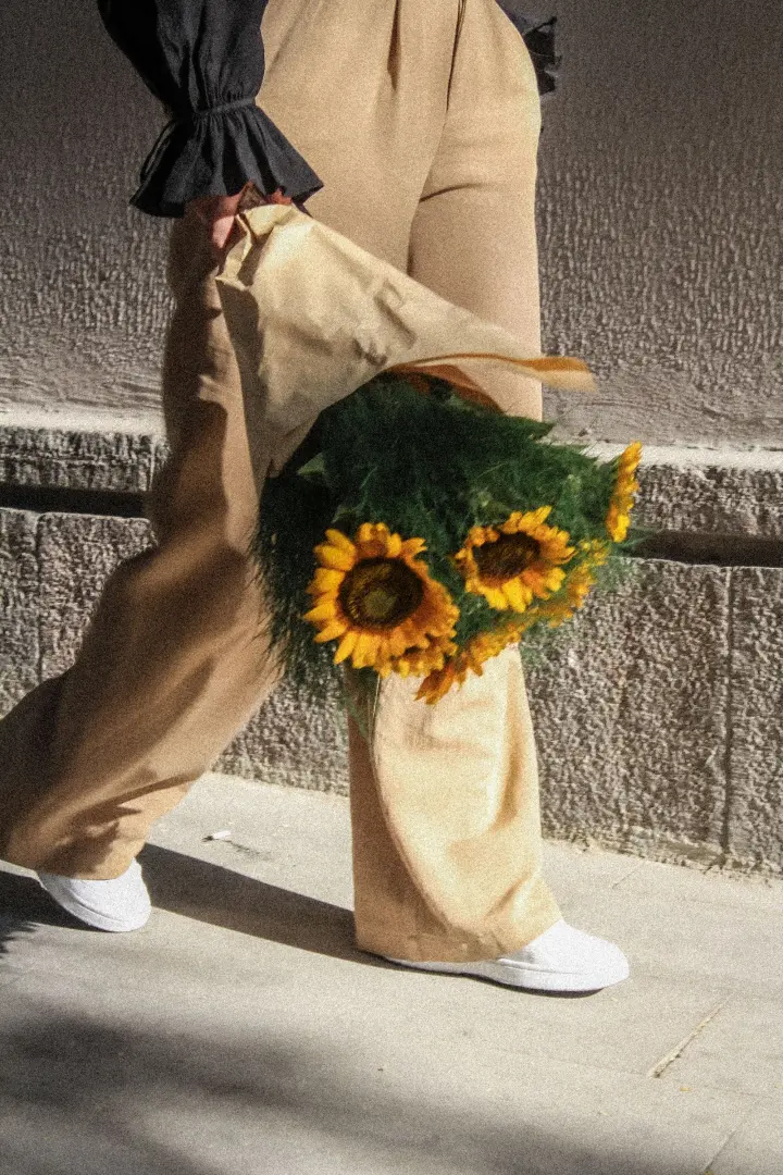 Persona caminando con un ramo de girasoles