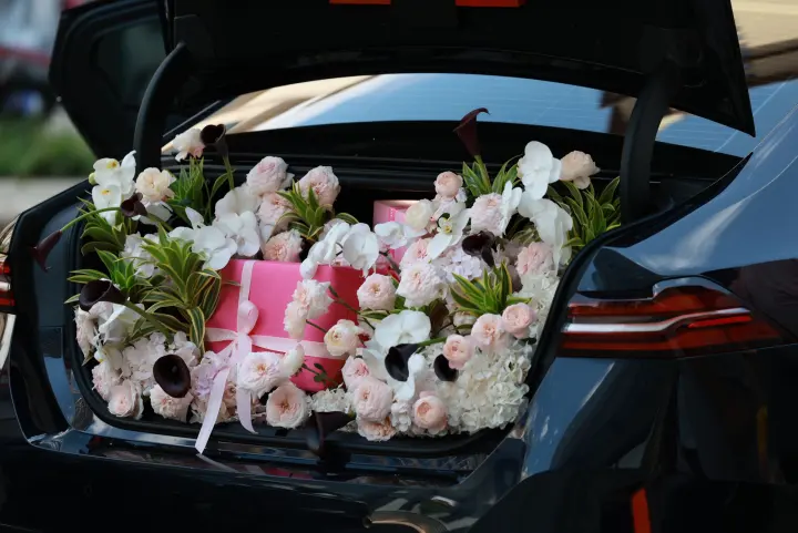Maletera de auto llena de flores y regalos rosados